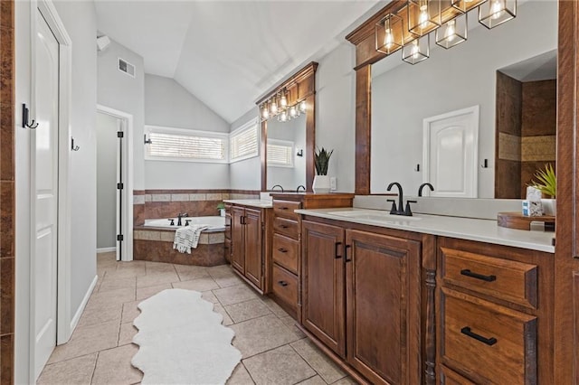 bathroom with a relaxing tiled tub, vaulted ceiling, vanity, and tile patterned flooring