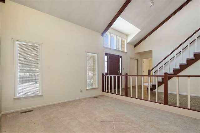 carpeted foyer entrance with beam ceiling and high vaulted ceiling