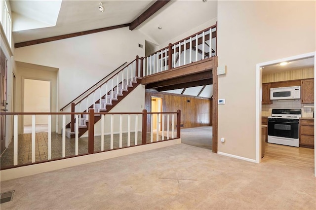 interior space with beam ceiling, high vaulted ceiling, and carpet flooring