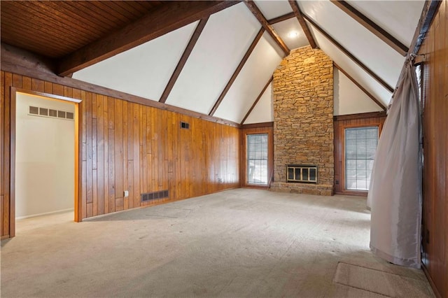 unfurnished living room featuring beam ceiling, a fireplace, wood walls, and high vaulted ceiling