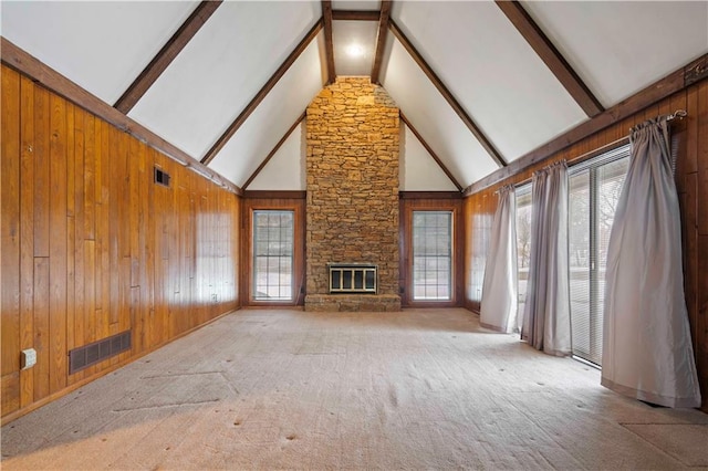 unfurnished living room with carpet floors, a fireplace, wood walls, high vaulted ceiling, and beam ceiling