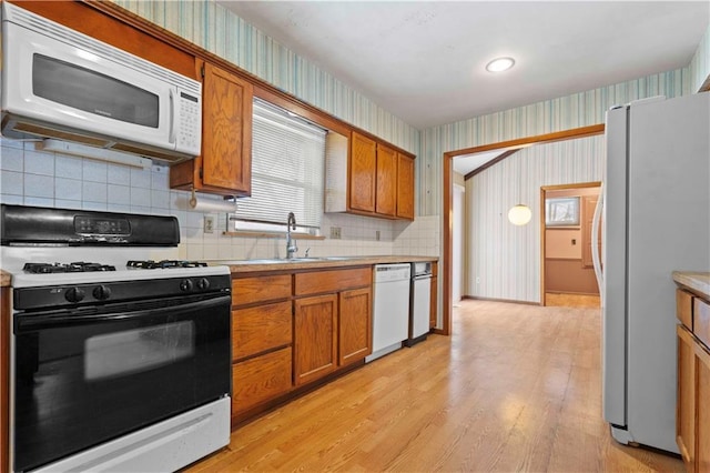 kitchen featuring light hardwood / wood-style floors, sink, white appliances, and tasteful backsplash