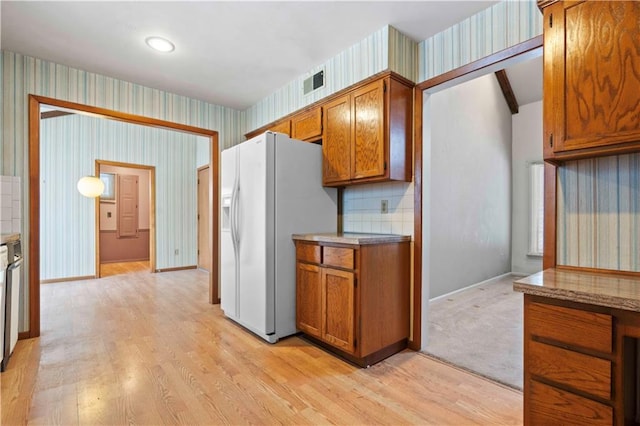 kitchen featuring tasteful backsplash, white refrigerator with ice dispenser, and light hardwood / wood-style flooring