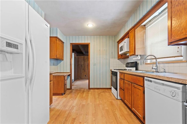 kitchen featuring sink, white appliances, and light hardwood / wood-style floors