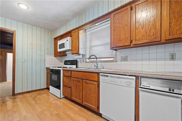 kitchen with light hardwood / wood-style floors, sink, white appliances, and decorative backsplash