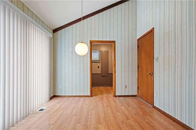 spare room with light hardwood / wood-style floors, ornamental molding, and lofted ceiling