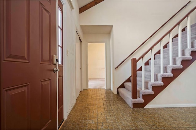 entryway with beam ceiling and a high ceiling