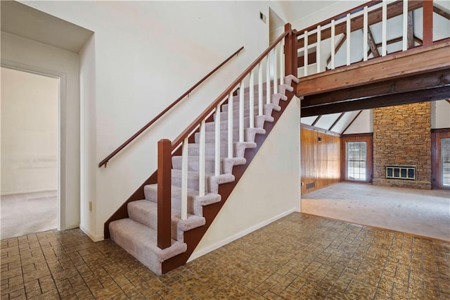 stairway with a stone fireplace and high vaulted ceiling