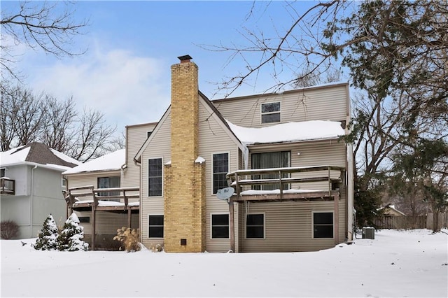 snow covered house with a deck and cooling unit