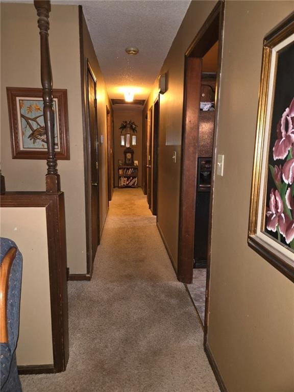 hallway featuring light carpet and a textured ceiling