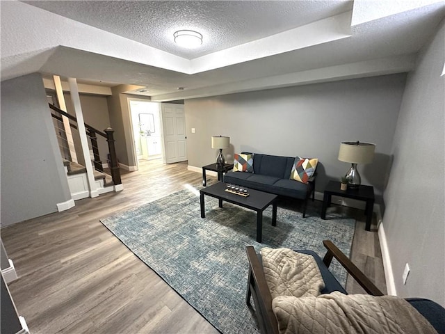 living room featuring a raised ceiling, a textured ceiling, and hardwood / wood-style flooring