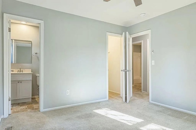 unfurnished bedroom featuring connected bathroom, light colored carpet, ceiling fan, and sink