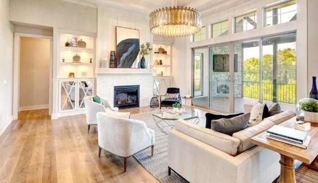 living room with a fireplace, a chandelier, built in features, and light wood-type flooring