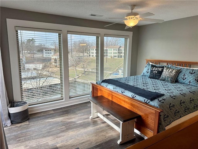 bedroom with wood-type flooring, a textured ceiling, and ceiling fan