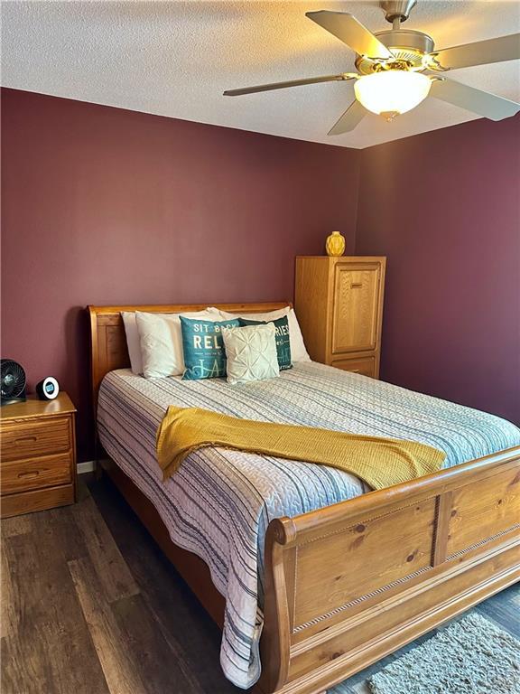 bedroom with ceiling fan, dark wood-type flooring, and a textured ceiling