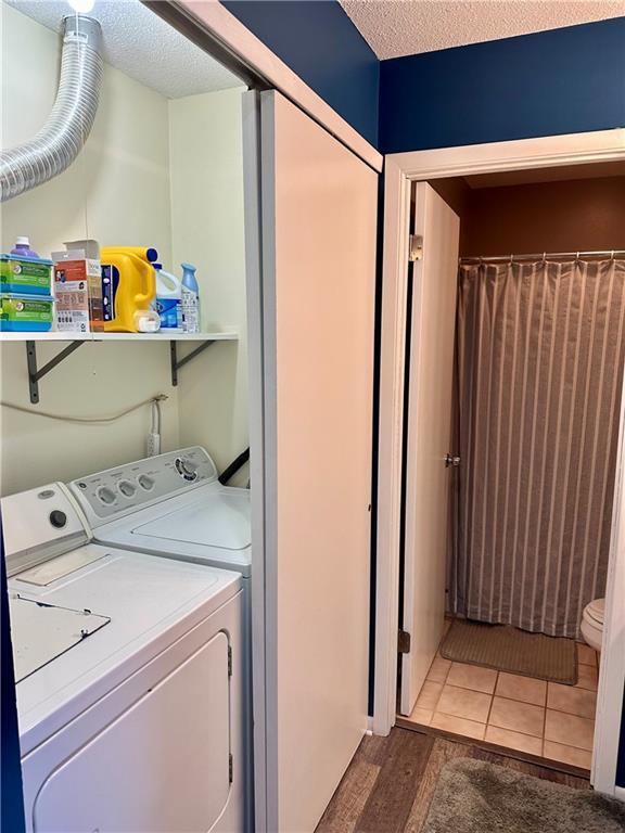 laundry area with tile patterned floors, washing machine and dryer, and a textured ceiling