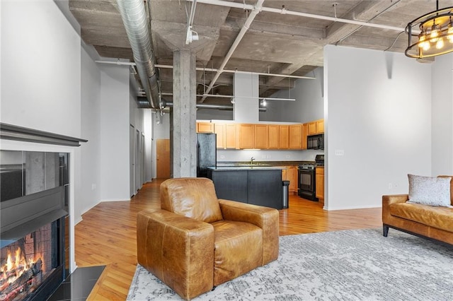 living room featuring a towering ceiling, light hardwood / wood-style flooring, and sink