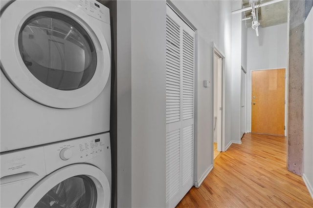 laundry area with hardwood / wood-style floors and stacked washer and clothes dryer