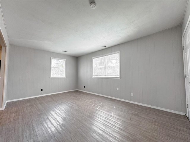 unfurnished room featuring hardwood / wood-style flooring and wooden walls