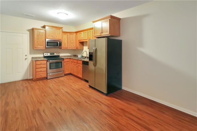 kitchen featuring light brown cabinetry, stainless steel appliances, light hardwood / wood-style floors, and sink