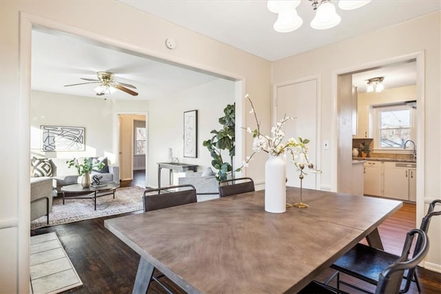 dining area featuring sink, wood-type flooring, and ceiling fan with notable chandelier