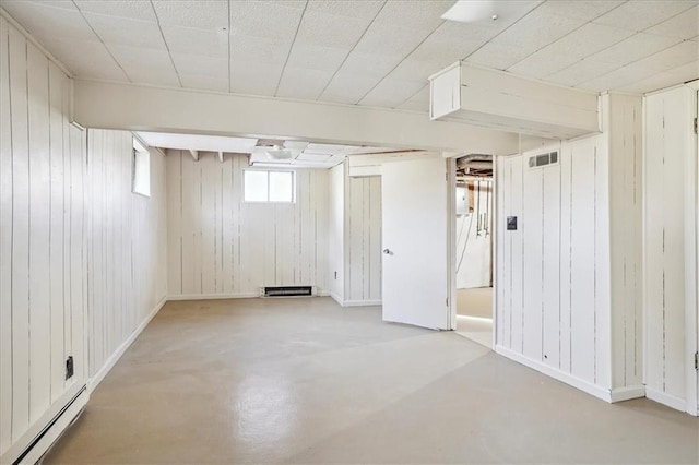 basement featuring baseboard heating and wooden walls