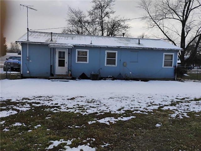 snow covered back of property featuring central AC