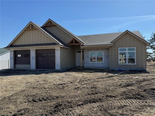 view of front facade featuring board and batten siding, a shingled roof, a garage, and dirt driveway