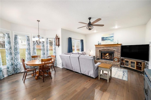 living room with dark hardwood / wood-style floors, ceiling fan with notable chandelier, and a fireplace