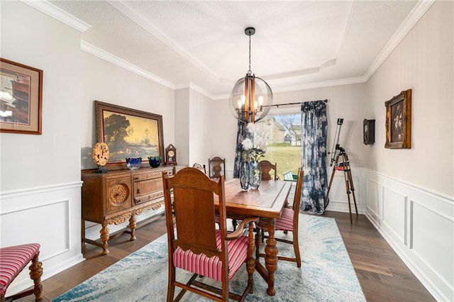 dining space with ornamental molding, dark hardwood / wood-style floors, a chandelier, and a tray ceiling