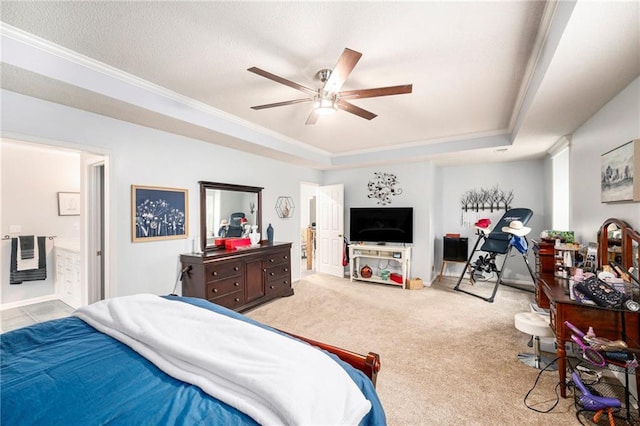 bedroom featuring a raised ceiling, ensuite bathroom, light carpet, and ceiling fan