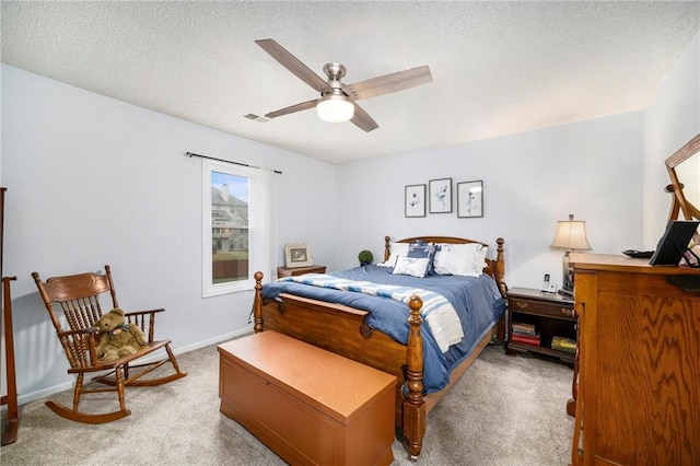 carpeted bedroom featuring ceiling fan and a textured ceiling