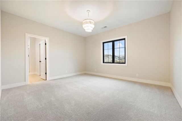 spare room featuring baseboards, visible vents, a chandelier, and light carpet