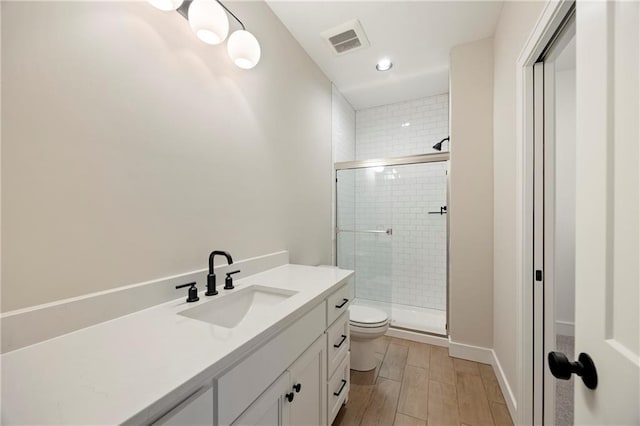 full bath featuring vanity, visible vents, wood tiled floor, a stall shower, and toilet