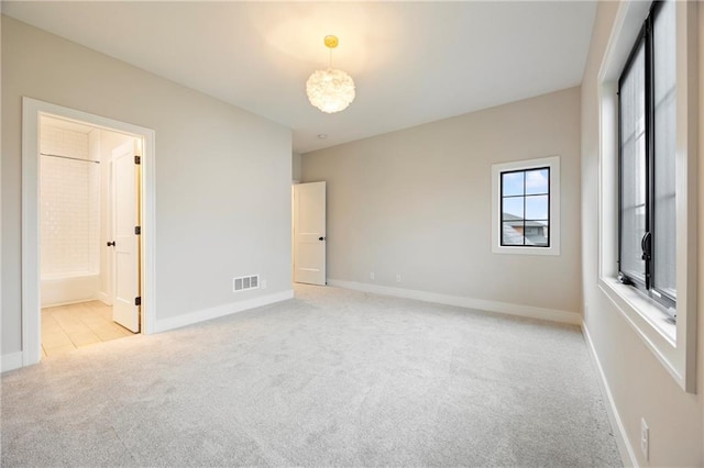 unfurnished bedroom featuring visible vents, baseboards, carpet, and ensuite bath