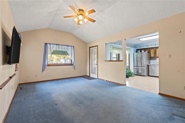 unfurnished living room with a textured ceiling, ceiling fan, light colored carpet, and lofted ceiling