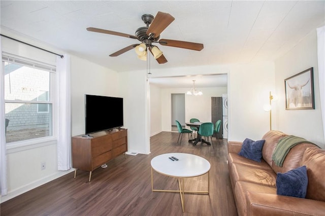 living room with ceiling fan with notable chandelier and dark hardwood / wood-style flooring