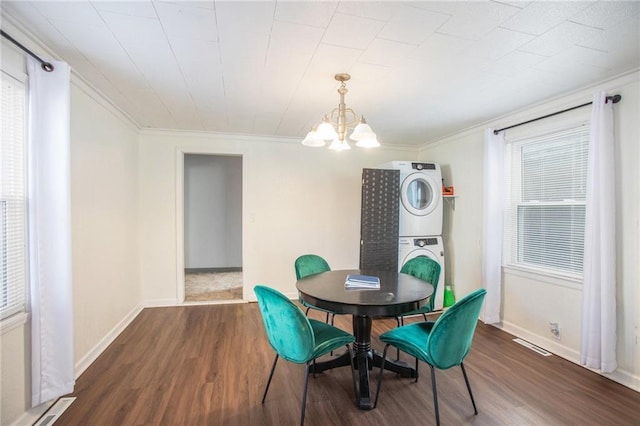 dining area featuring ornamental molding, hardwood / wood-style flooring, stacked washer / dryer, and a notable chandelier