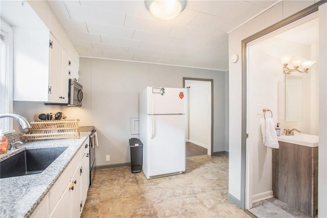 kitchen with light stone countertops, sink, white cabinets, and white refrigerator