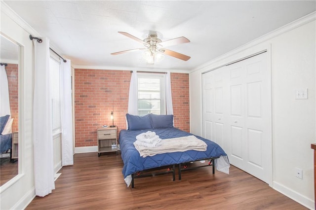 bedroom with ceiling fan, dark hardwood / wood-style floors, and brick wall