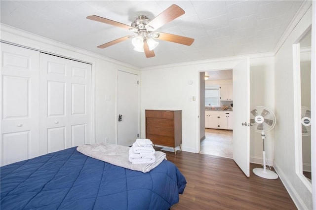 bedroom with a closet, ceiling fan, crown molding, and dark wood-type flooring