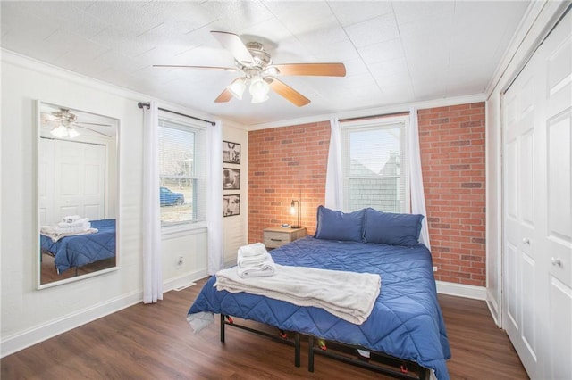 bedroom featuring dark wood-type flooring, ceiling fan, crown molding, and brick wall