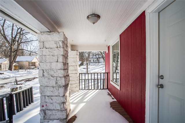 snow covered back of property featuring a porch