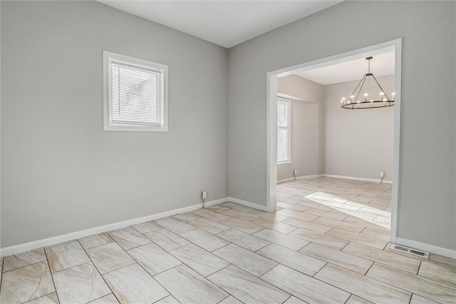 unfurnished room featuring plenty of natural light and a chandelier