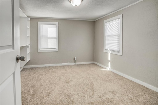 unfurnished room featuring light colored carpet, a textured ceiling, and ornamental molding