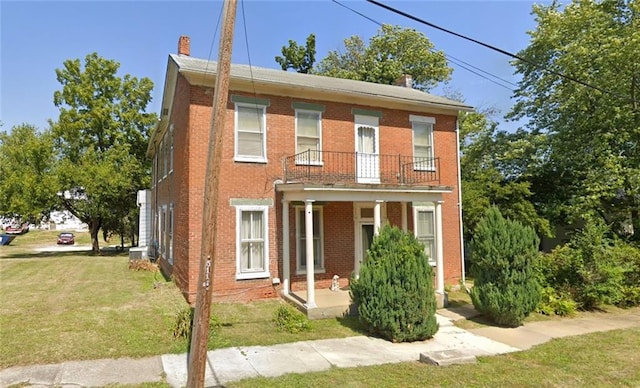 view of front facade with a front yard and a balcony