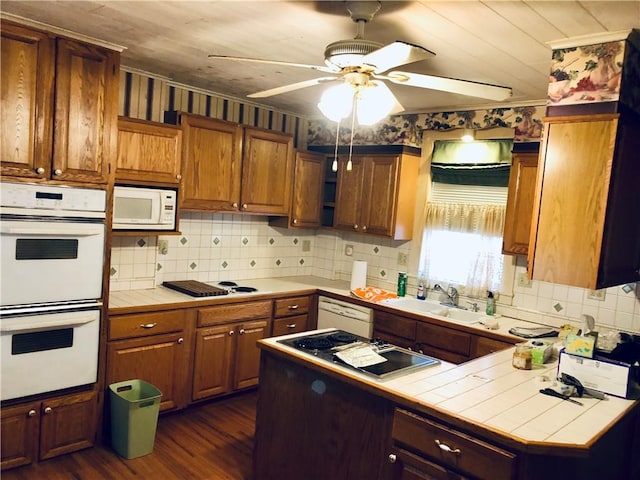 kitchen featuring dark hardwood / wood-style flooring, white appliances, ceiling fan, sink, and tile countertops