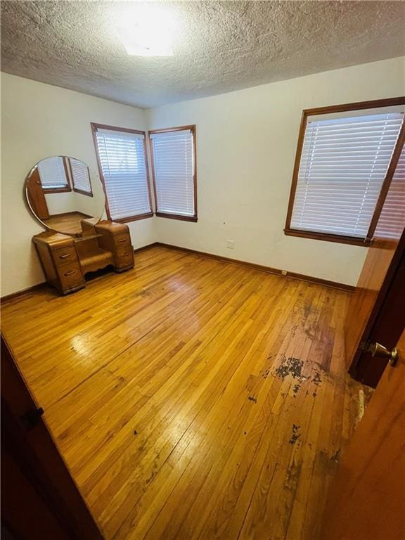 spare room featuring a textured ceiling and light hardwood / wood-style floors