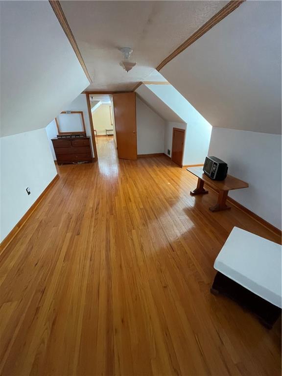 bonus room with light hardwood / wood-style flooring and vaulted ceiling