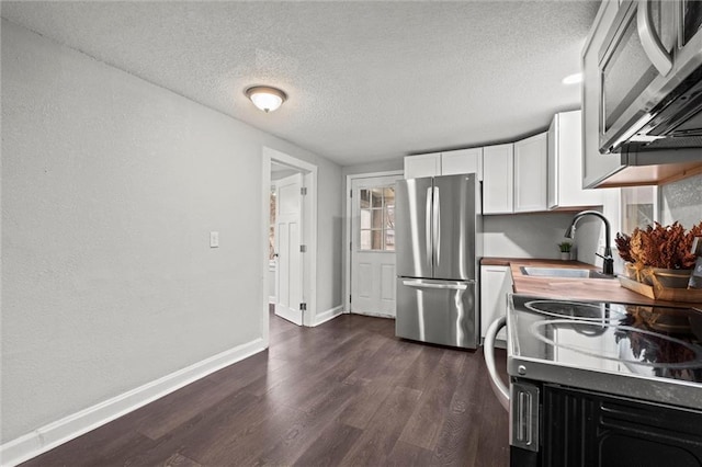 kitchen featuring sink, a textured ceiling, appliances with stainless steel finishes, dark hardwood / wood-style flooring, and white cabinetry